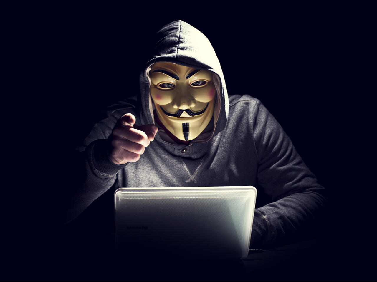 Hacker wearing a Guy Fawkes mask using a laptop